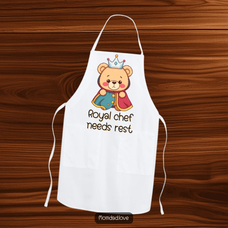 Funny apron showing a bewildered teddy bear dressed in a tiny crown and royal robe, for a humorous and slightly confused culinary experience.